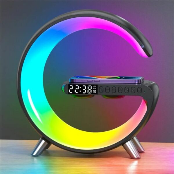 Lampe réveil multifonction allumée sur la fonction lumière multicolore et posée sur un meuble, sur fond de dégradé de gris.