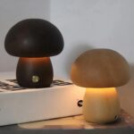 Petite lampe tactile champignon en bois, posée sur un livre dans une chambre.