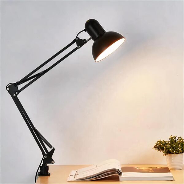 Lampe architecte à pince noire, mise en scène sur un bureau et allumée.