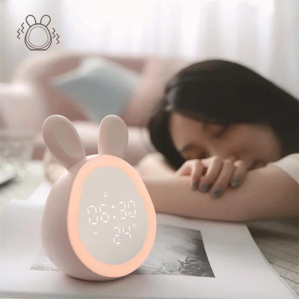 Lampe réveil lapin mignon sur une table à côté d'une jeune fille qui dort.
