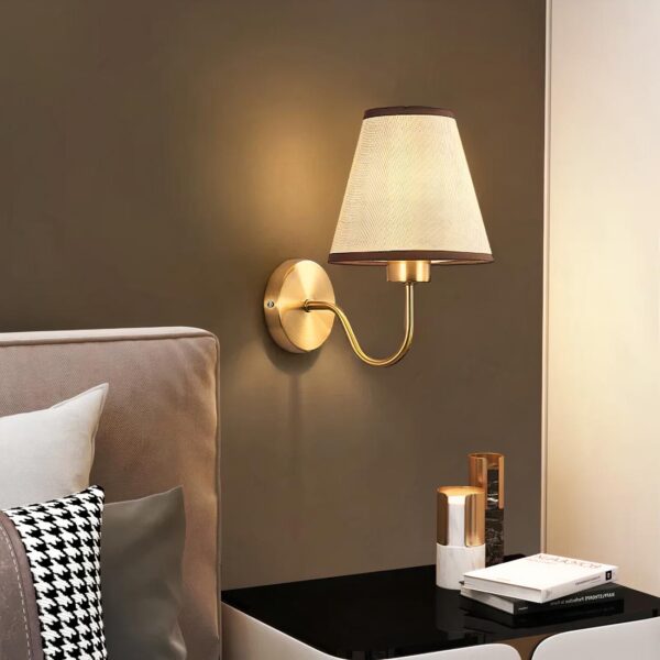 Lampe de chevet murale style scandinave allumée et fixée sur un mur à côté d'un lit dans une chambre à coucher.