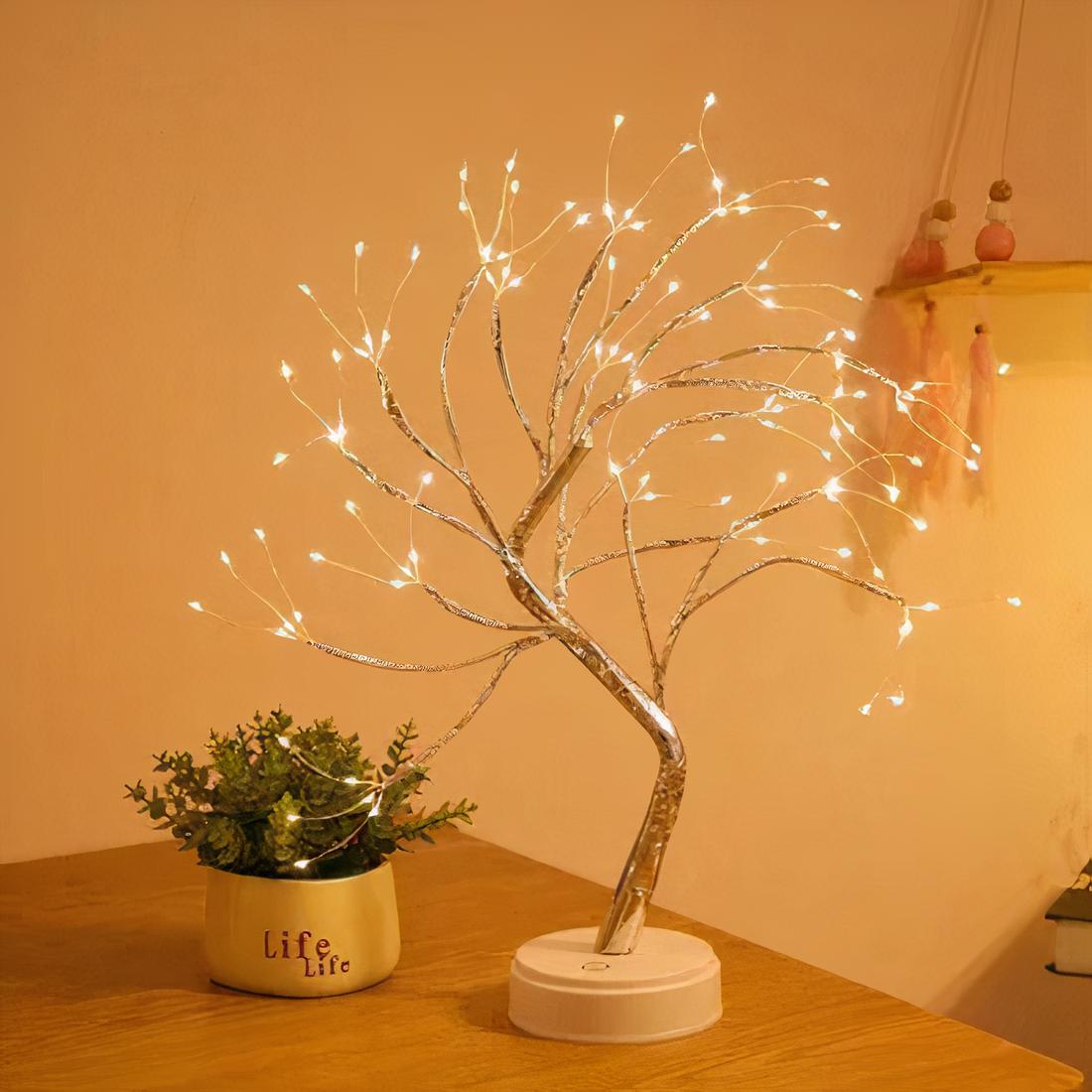 Lampe de chevet tactile arbre de vie à LED, allumé et posé sur un meuble en bois, à côté d'une petite plante grasse.