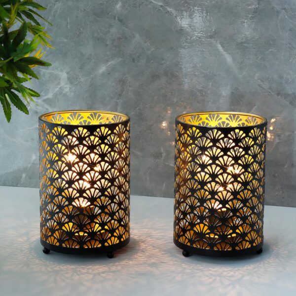 Duo de lampes de chevet en métal motif éventails, allumé et posé sur un meuble gris, sur fond gris.