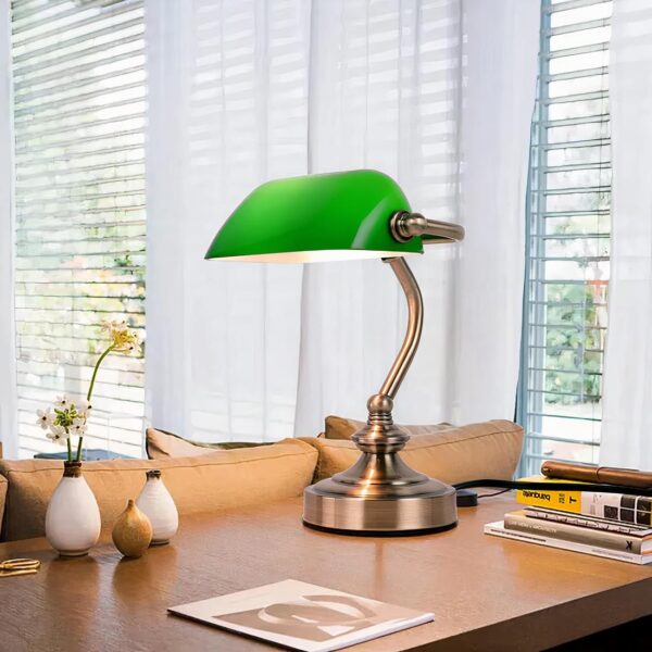 Lampe rétro en métal avec un abat-jour vert posée sur un bureau dans une pièce meublée et décorée.