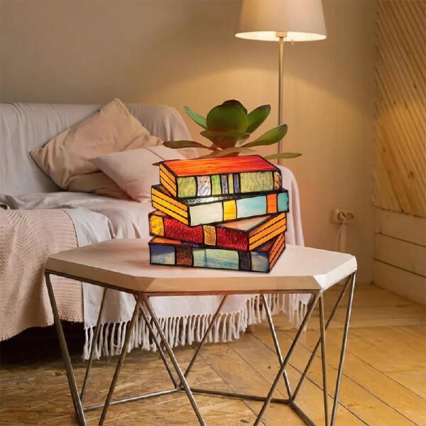 Lampe de chevet baroque en forme de livre empilés posé sur une petite table devant un canapé