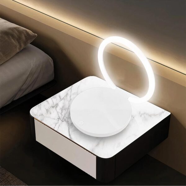 Lampe de chevet charge rapide sans fil pour smartphone allumée avec un téléphone en charge sur sa base et posée sur une table en bois.