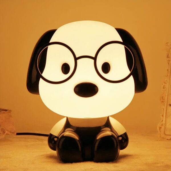Lampe de chevet chien mignon allumée et posée sur un meuble, sur fond uni.