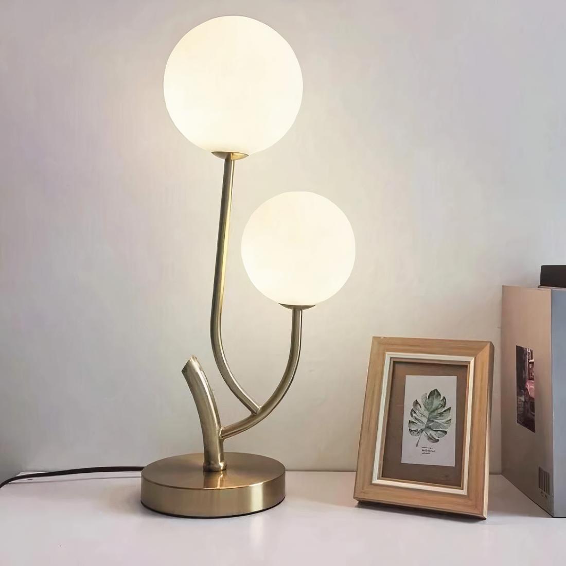 Lampe de chevet cocooning a double tête posé sur une table à côté d'un cadre
