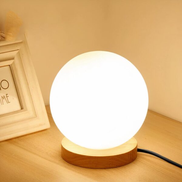 lampe de chevet cocooning en forme de boule posé sur une table près d'un cadre