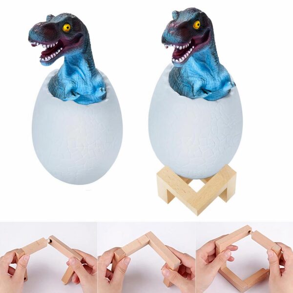 Lampe de chevet dinosaure dans son œuf, allumée et posée sur un meuble à côté d'une pile de livres.