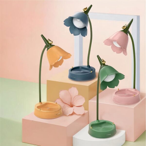 Lampe de chevet fille fleur en métal dans chaque couleur, posée sur un socle et sur fond rose et vert.