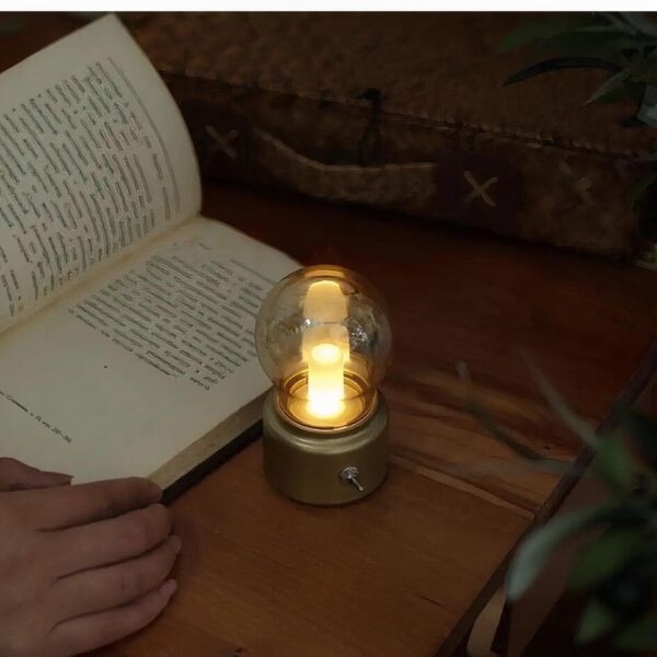 Lampe de chevet LED forme ampoule allumée et à côté d'une personne qui lit un livre.