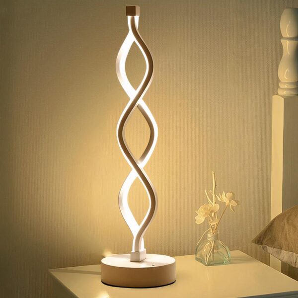 Lampe de chevet moderne en forme de spirale posé sur une table de chevet à côté d'un petit vase