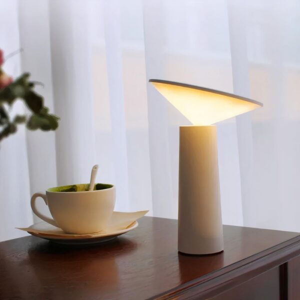Lampe de chevet sans fil et rechargeable design atypique sur une table de chevet et à côté d'une tasse de café.