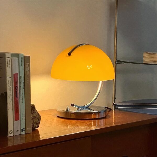 Lampe de chevet style industriel allulmée et en version jaune, posée sur un meuble en bois à côté d'une pile de livres.