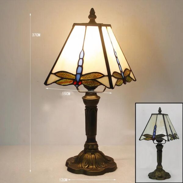Lampe style Tiffany avec un abat-jour carré avec une libellule, allumée et posée sur un support
