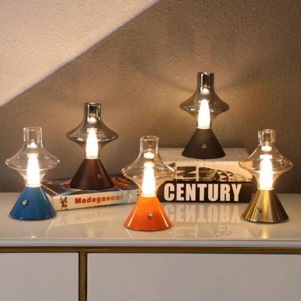 Lampe de chevet vintage rechargeable en verre dans toutes ses variantes de couleur, allumée et posée sur un meuble laqué blanc.