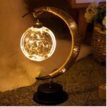 Lampe lune ampoule suspendue, allumée et posée sur un meuble.