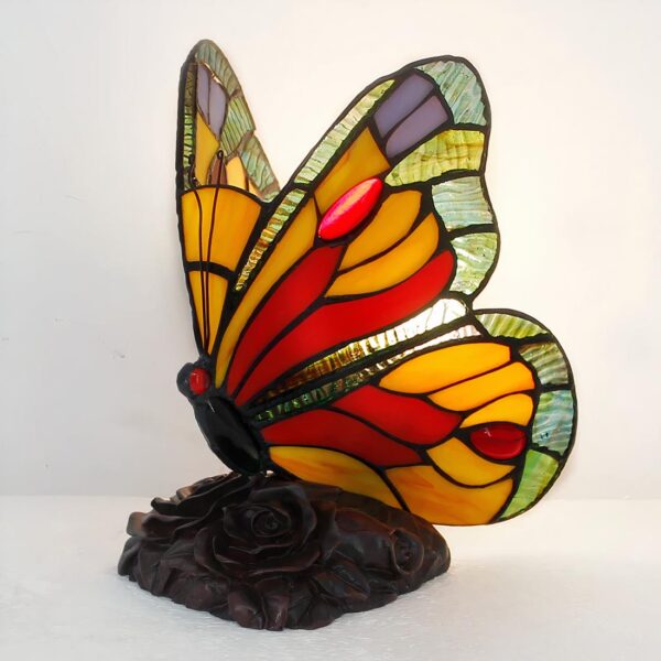Lampe style Tiffany en forme de papillon coloré, sur un socle marron foncé en forme de rose.