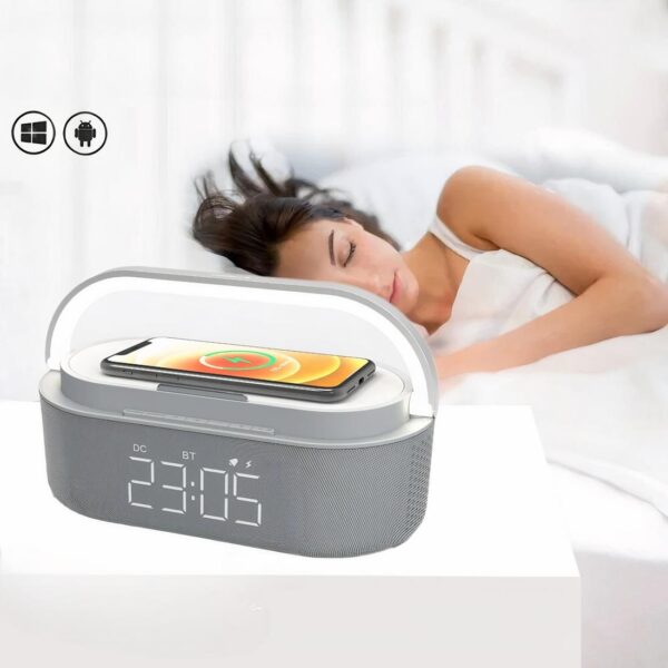 Radio réveil lampe de chevet et chargeur de téléphone en avant plan avec une femme qui dort dans son lit en arrière-plan.