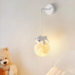 Lampe de chevet en forme d'ours pour bébé accroché sur un mur près d'un lit