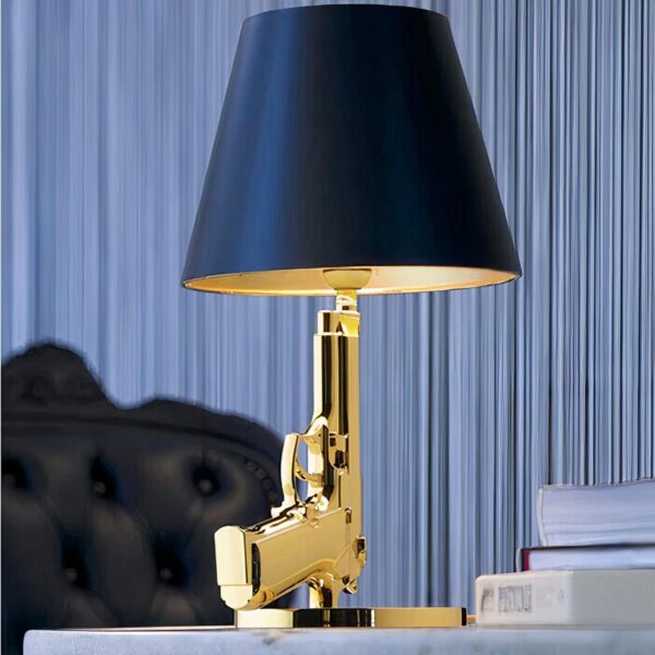 Lampe de chevet originale en forme de pistolet posé sur une table près d'un lit