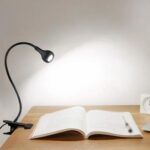 Lampe de chevet pince posé sur une table près d'un livre