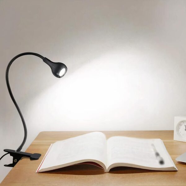 Lampe de chevet pince posé sur une table près d'un livre