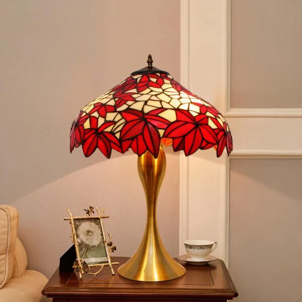 Lampe e chevet Tiffany en forme de feuilles d'érable rouge posé sur une table de chevet près d'un lit