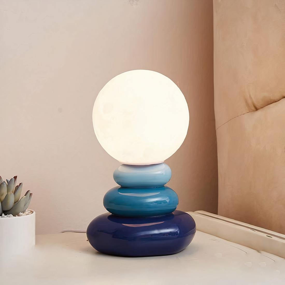 IMG_lampe_de_chevet_galet_bleu Lampe de chevet galet bleu posé sur une table près d'une plante