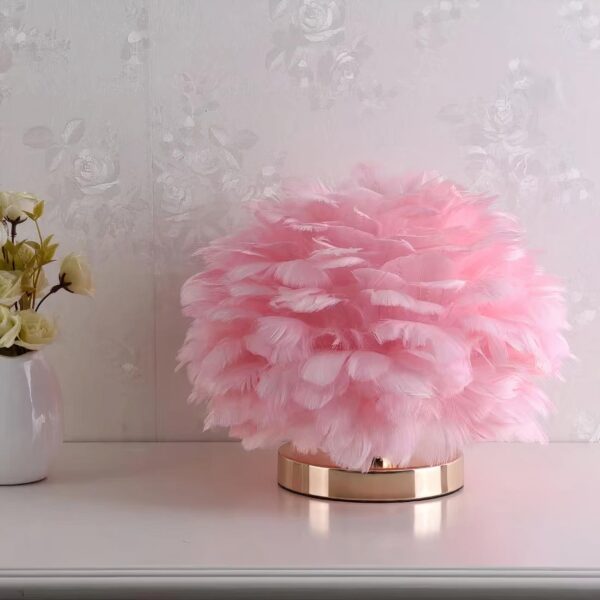 Lampe de chevet plume rose posé sur une table