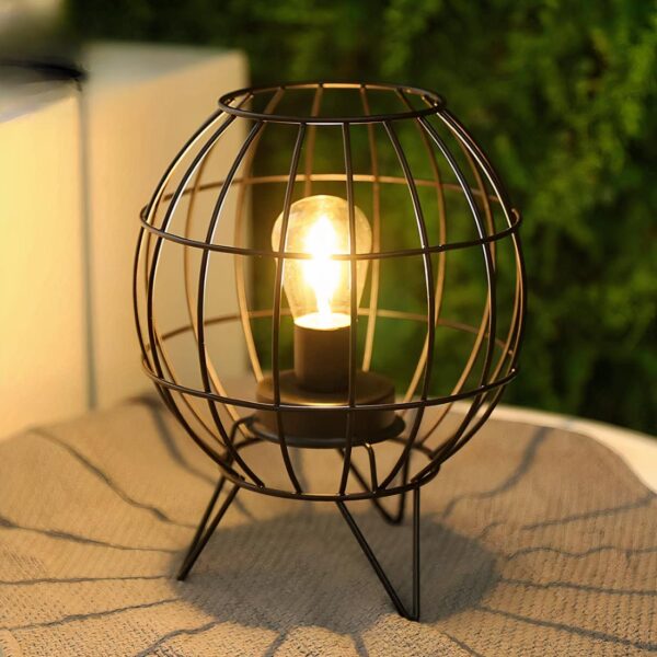 Lampe à pile en cage métallique arrondie posée sur une table