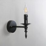 Lampe de chevet murale en forme de bougeoir noir et une ampoule en forme de flamme éteinte. Fixée au mur.