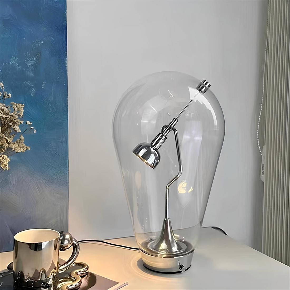 Une lampe de chevet en forme d'ampoule posée sur une table blanche avec une tasse vintage en porcelaine à gauche. Derrière le mur et blanc et la partie la plus à gauche est bleue. La lumière est allumée et éclaire derrière la tasse.