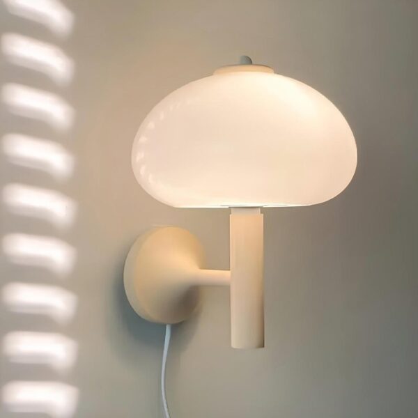 Lampe murale blanche avec un abat-jour en forme de champignon accrochée à un mur gris dans une pièce.