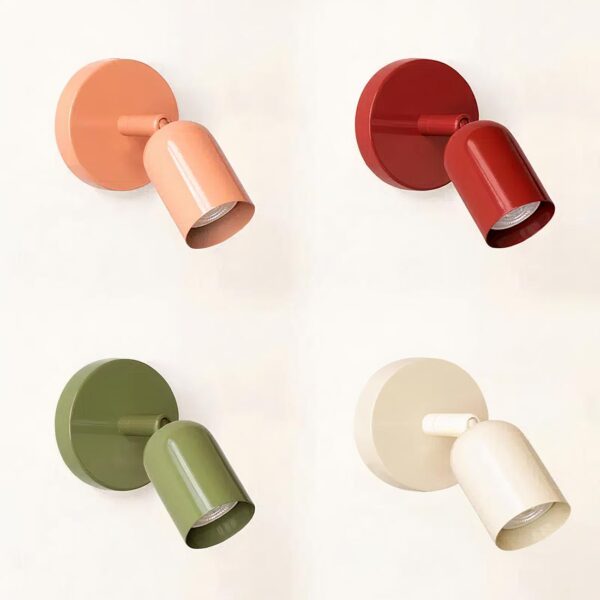 Quatre lampes de chevet murales dans chaque coin, en haut à gauche rose, en haut à droite rouge, en bas à gauche verte, en bas à droite blanche. Socle rond sur le mur et tête orientable comme un spot. Sur fond blanc.