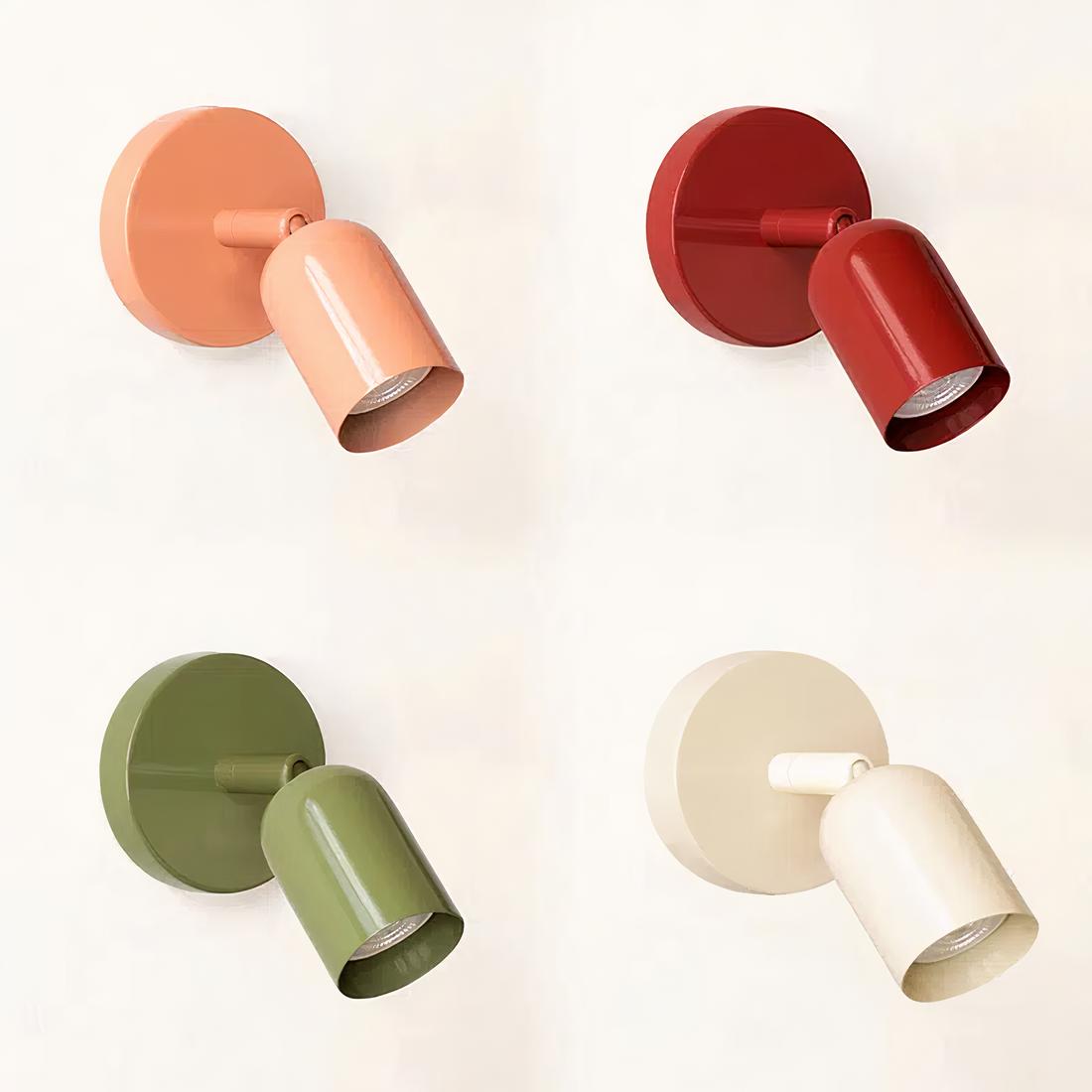 Quatre lampes de chevet murales dans chaque coin, en haut à gauche rose, en haut à droite rouge, en bas à gauche verte, en bas à droite blanche. Socle rond sur le mur et tête orientable comme un spot. Sur fond blanc.