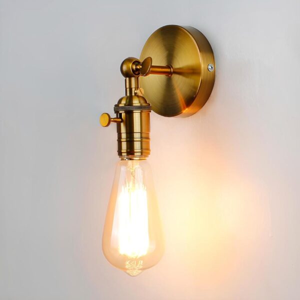 Lampe de chevet murale de style industriel de couleur dorée avec rond sur le mur et tige avec douille et une ampoule allumée.