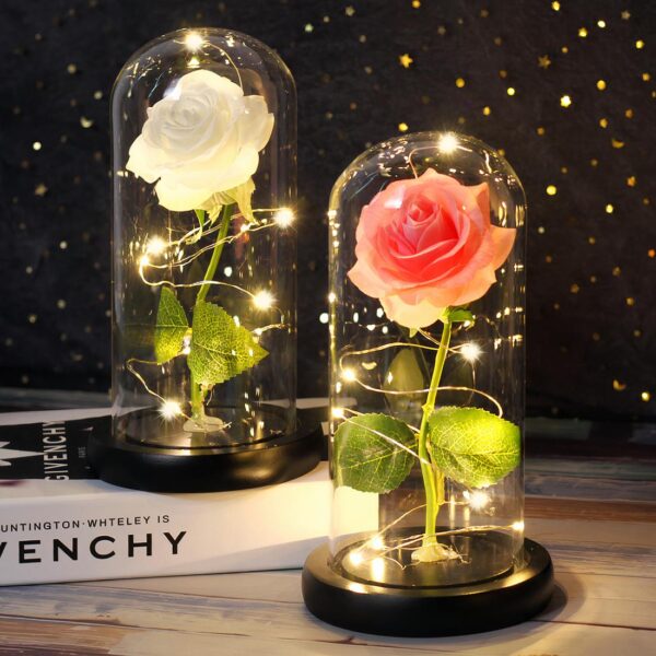 Deux lampes à piles avec des roses éternelles dans un support en verre et posées sur une table