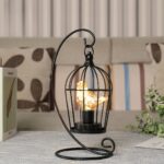 Une lampe à pile en forme de cage noire avec un oiseau éclairé à l'intérieur