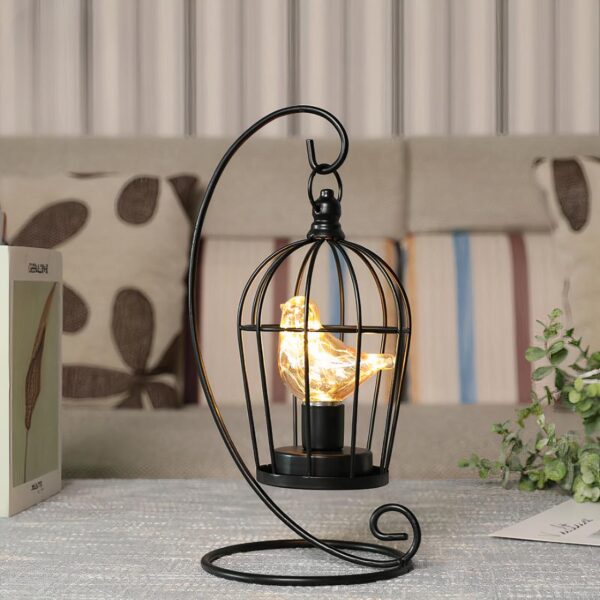 Une lampe à pile en forme de cage noire avec un oiseau éclairé à l'intérieur
