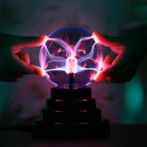Une lampe boule en verre plasma allumée sur un fond sombre avec des mains dessus