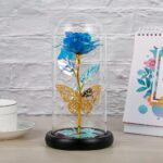 Une lampe à pile avec une rose et un papillon à l'intérieur d'une cloche en verre