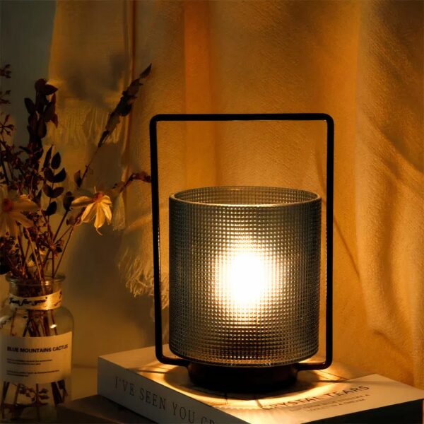 Lampe de chevet à pile style lanterne en verre posée sur une table de chevet