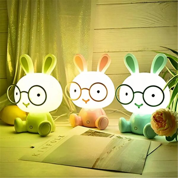 trois lampes lapins LED avec lunettes vert, rose et bleu assis sur une table