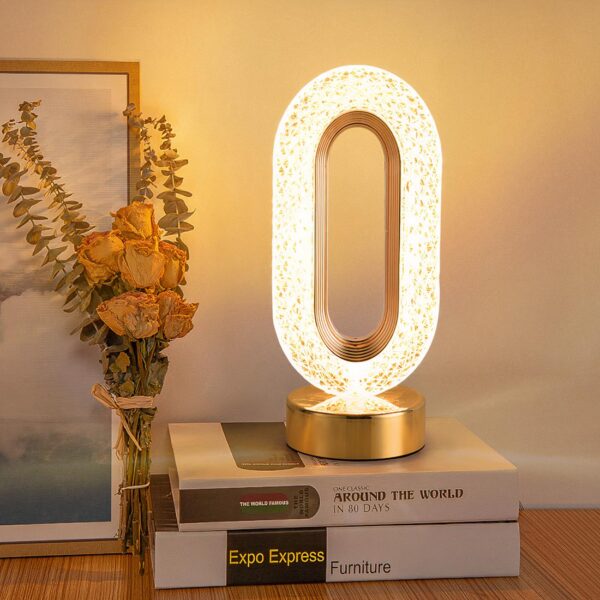 Une lampe de chevet style cristal allumée posée sur deux livres sur une table