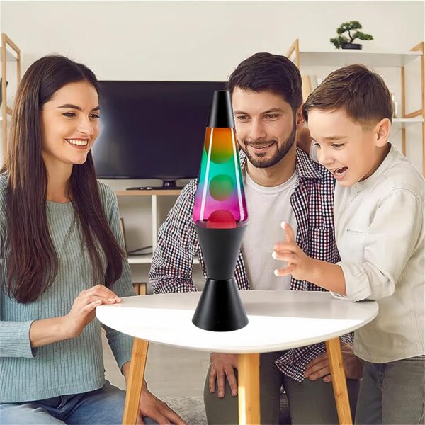 Une lampe à lave multicolore relaxante posée sur une table basse avec autour une famille