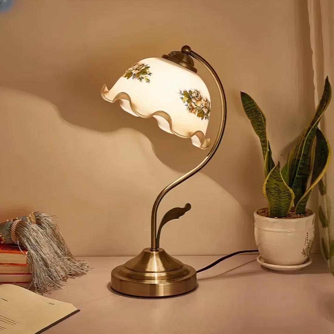 Une lampe de chevet vintage avec abat jour en verre fleuri sur une table