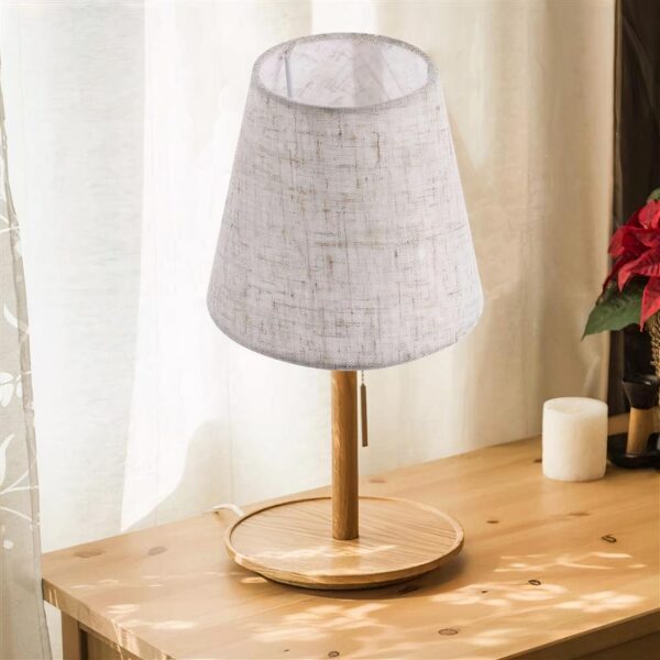 Un abat jour en tissu rustique gris posé sur une table en bois