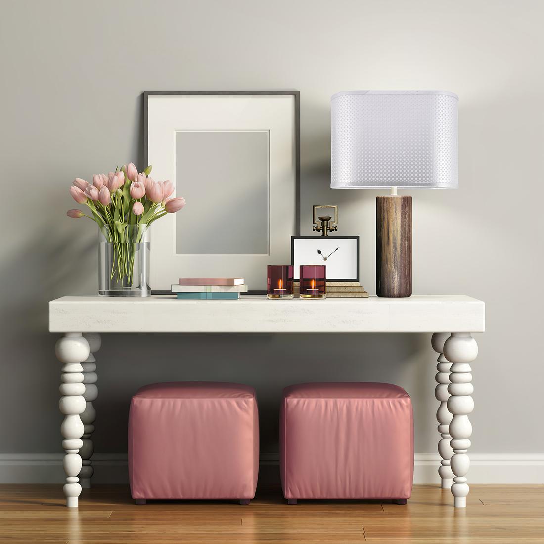 Un abat-jour oval en tissu à grille argenté posé sur un meuble d'entrée